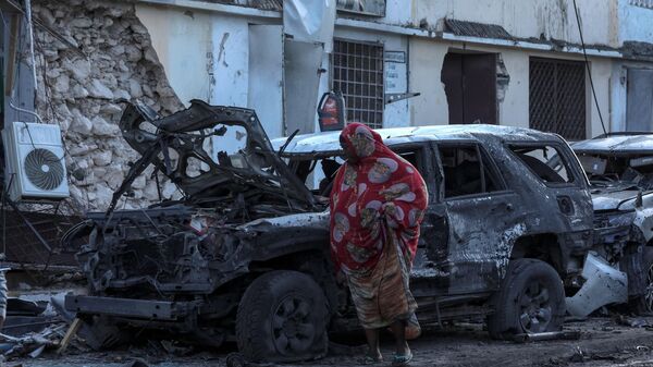 A woman walks past debris and destruction at a cafe in Mogadishu on July 15, 2024 following a car bomb blast where five people were killed where football fans were watching the Euro 2024 final late on July 14, 2024.  - Sputnik Africa