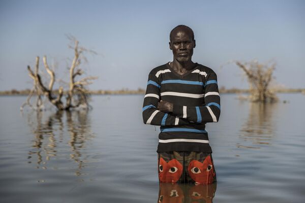 Cette photohraphie de Luke Dray est intitulée La réalité climatique du Soudan du Sud. Elle fait partie des finalistes du concours international de photojournalisme Stenine 2024. John Malesh, 40 ans, pose pour un portrait là où se trouvait autrefois sa maison, le 29 novembre 2023 à Tong, au Soudan du Sud. Lui et sa famille vivent sur un petit terrain surélevé, entouré d’eaux de crue, depuis que leurs champs ont été inondés en 2021. Lorsqu’on l’interroge sur la menace d’El Niño pour l’année prochaine, il répond :  S’il pleut beaucoup cette année, cette terre ne sera plus là.  - Sputnik Afrique