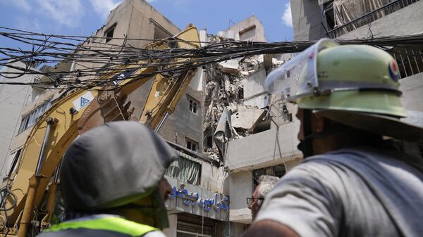 Hezbollah Civil Defense members stand in front of a building that was destroyed by an Israeli airstrike Tuesday night in a southern suburb of Beirut, Lebanon, Wednesday, July 31, 2024. - Sputnik Africa