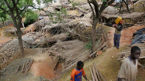 Men walk near mine shafts covered with reed roofs on a hillside containing hundreds of artisanal mines, near the village of Tenkhoto, Senegal - Sputnik Africa