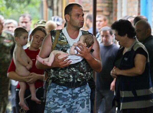 A special forces soldier carries a baby and a woman carries a child after being released by militants in Beslan, North Ossetia. - Sputnik Africa