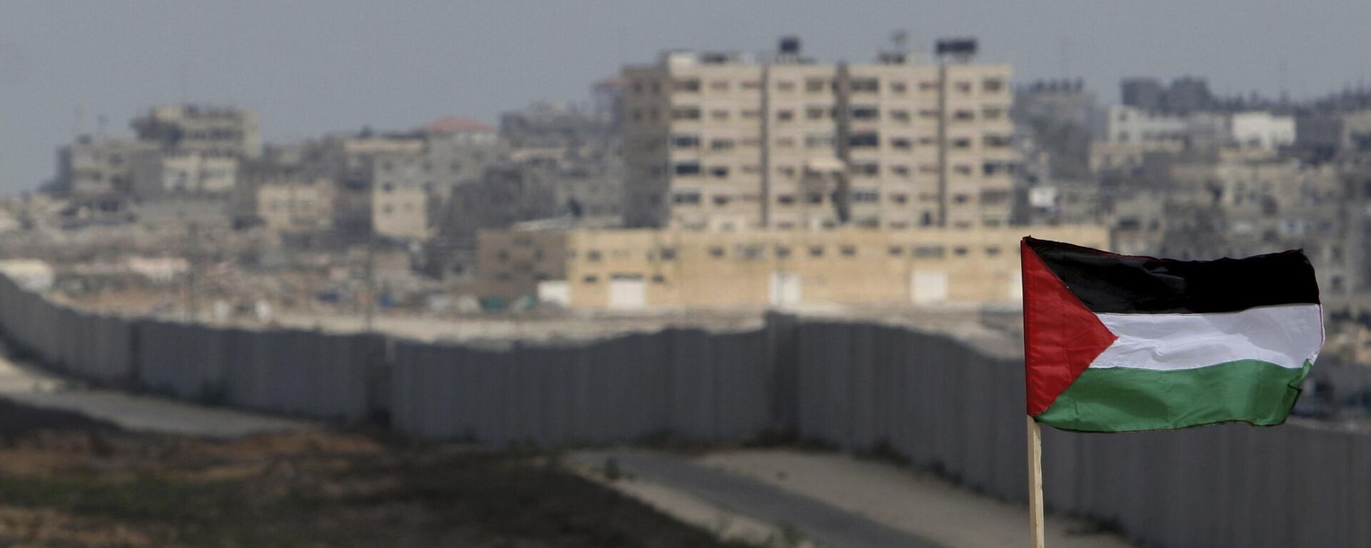 FILE - A Palestinian flag is seen with the background of a section of the wall in the Philadelphi corridor between Egypt and Gaza, on the background, near the southern Gaza Strip town of Rafah. - Sputnik Africa, 1920, 01.09.2024