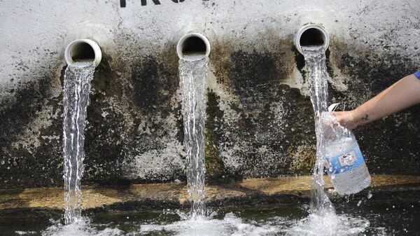 Tarah Nogrady collects water from a trough, Sunday, July 26, 2020, in Athens, Ohio.  - Sputnik Africa