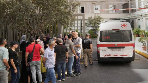 Lebanese Red Cross ambulance passes next of the families of victims who were injured on Monday by their exploding handheld pagers, at the emergency entrance of the American University hospital, in Beirut, Lebanon - Sputnik Africa