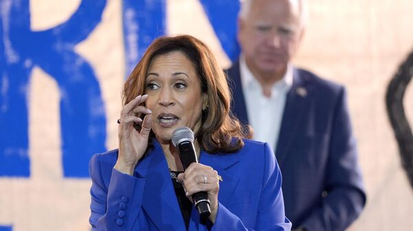 Democratic presidential nominee Vice President Kamala Harris speaks as Democratic vice presidential nominee Minnesota Gov. Tim Walz listens at a campaign event, Sunday, Aug. 18, 2024, in Rochester, Pa. - Sputnik Africa