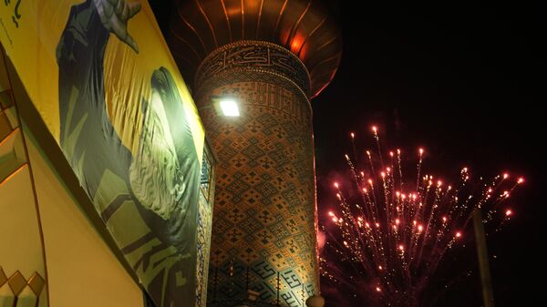 Des feux d'artifice explosent à côté d'un portrait du chef assassiné du Hezbollah, Hassan Nasrallah, et d'un minaret d'une mosquée lors d'un rassemblement anti-israélien célébrant la frappe de missiles iraniens contre Israël, sur la place Felestin (Palestine) à Téhéran, en Iran, le mardi 1er octobre 2024. (AP Photo/Vahid Salemi) - Sputnik Afrique