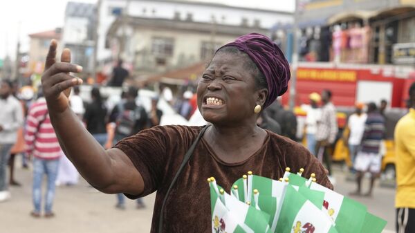 Une femme vendant des drapeaux nigérians lors d'une manifestation contre les difficultés économiques dans les rues de Lagos, au Nigeria, le 1er octobre 2024.  - Sputnik Afrique