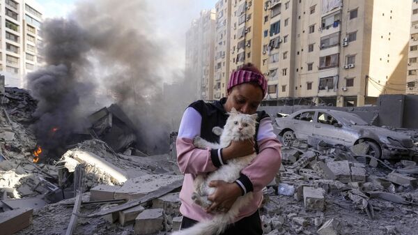 A woman holds her cat in front of a destroyed building at the site of an Israeli airstrike in Dahiyeh, Beirut, Lebanon, Wednesday, Oct. 2, 2024. - Sputnik Africa