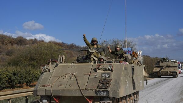 Israeli soldiers raise their fists from a moving APC in northern Israel near the Israel-Lebanon border, Tuesday, Oct. 1, 2024.  - Sputnik Africa