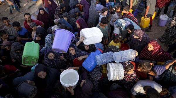 Palestinians displaced by the Israeli bombardment of the Gaza Strip queue for water at a makeshift tent camp in the southern town of Khan Younis, Monday, July 1, 2024 - Sputnik Africa