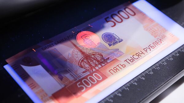 Verification of the authenticity of the updated 5,000-ruble Bank of Russia banknote using an ultraviolet light device. - Sputnik Africa