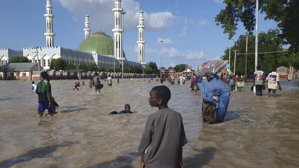 People walk through floodwaters following a dam collapse in Maiduguri, Nigeria, Tuesday, Sept 10, 2024 - Sputnik Africa