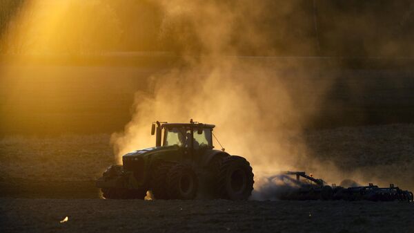 A tractor ploughs the land in a field during a sunset on the outskirts of Minsk, Belarus, Wednesday, April 8, 2020. - Sputnik Africa