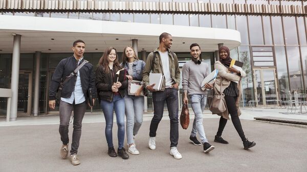 Multi-ethnic university students walking against building in campus - Sputnik Africa