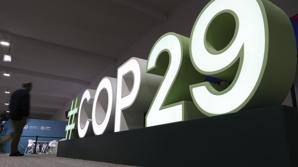 An attendee walks near a sign for the COP29 UN Climate Summit, Saturday, Nov. 9, 2024, in Baku, Azerbaijan.  - Sputnik Africa