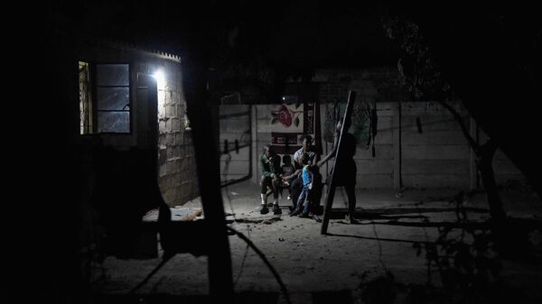 A family sit outside and share food by torchlight, after darkness falls in the Harare suburb of Chitungwiza where electricity is only provided for a few hours, usually after around 9pm, Chitungwiza, Zimbabwe on October 8th 2015. - Sputnik Africa