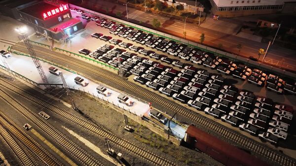 Workers drive SUVs made by Great Wall Motor onto a freight train bound for Russia at a designated freight station in Yongchuan district in southwest China's Chongqing Municipality. - Sputnik Africa