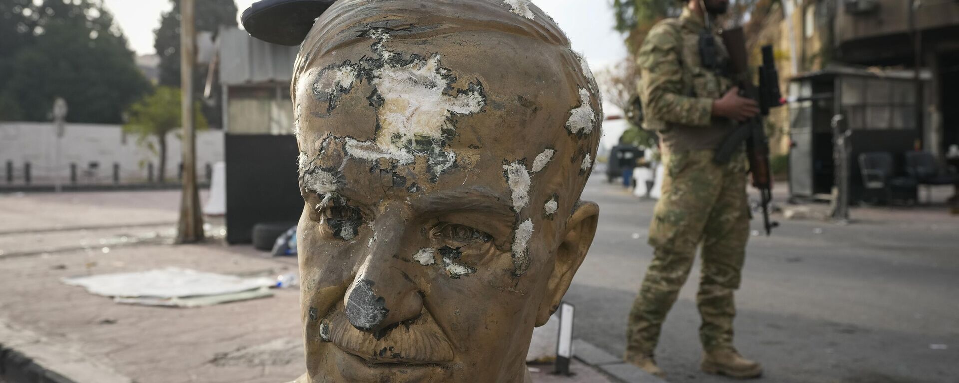 An opposition fighter in military uniform stands next to a broken bust of the late Syrian President Hafez Assad, with a pair of shoes placed on top, at a checkpoint in Damascus, Syria, Wednesday, Dec. 11, 2024. - Sputnik Africa, 1920, 01.01.2025