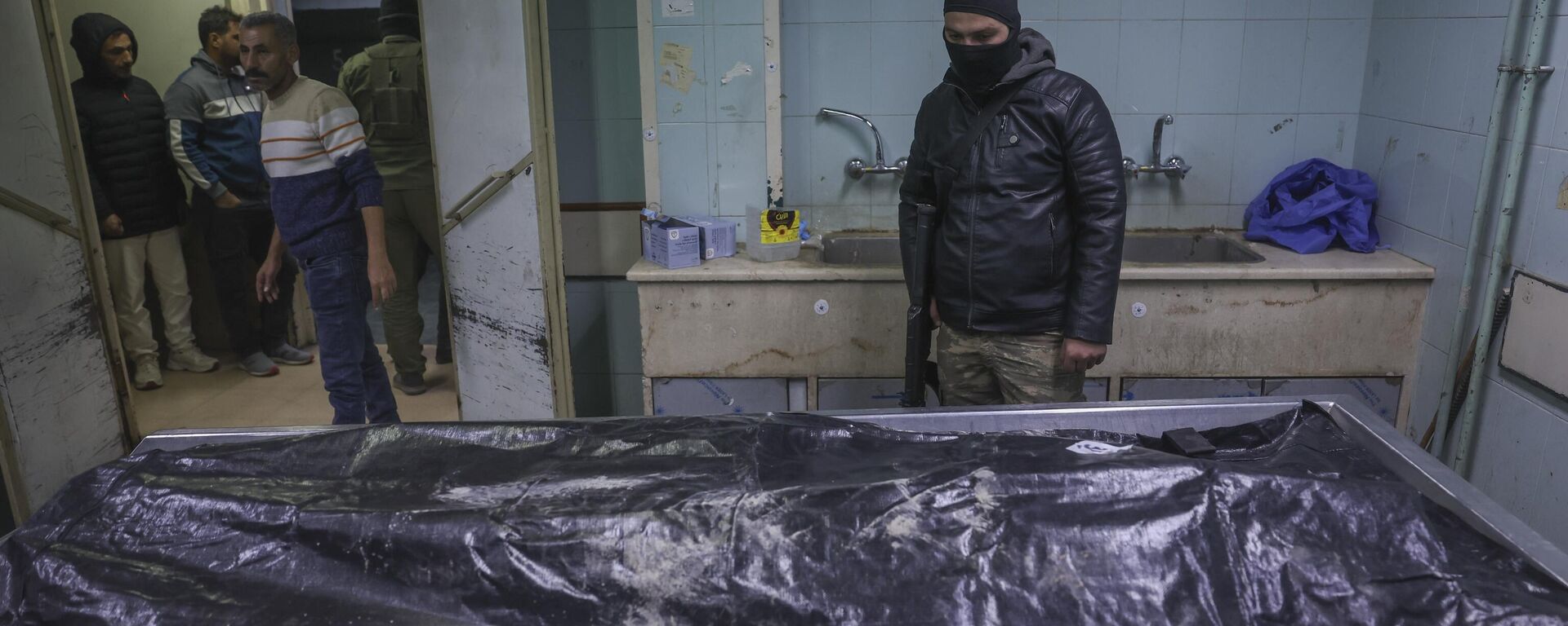 A body lies at the morgue as people stands while waiting to identify missing relatives or friends at the morgue of Al-Mujtahidh hospital in Damascus, Syria, Tuesday, Dec. 10, 2024. - Sputnik Africa, 1920, 11.12.2024