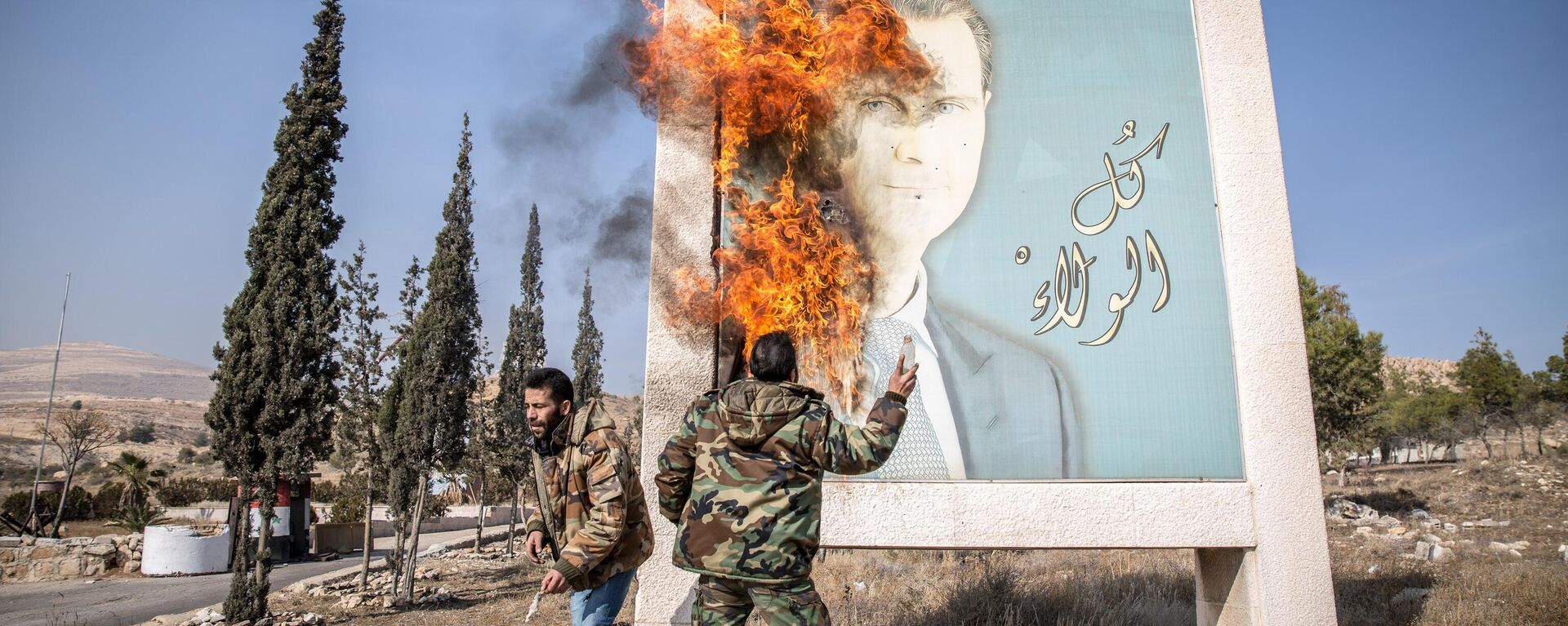 DAMASCUS, SYRIA - 2024/12/10: A man burns a picture of former Syrian president Bashar al-Assad close to Syria's border with Lebanon. Rebels launched a shock offensive across Syria in late November, ousting President Bashar al-Assad and ending more than half a century of the Assad family regime. - Sputnik Africa, 1920, 11.12.2024