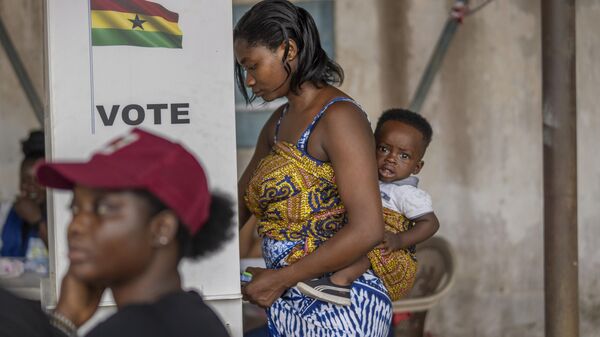 A woman with her child prepares her ballot in the general elections in Accra, Ghana, Saturday, Dec. 7, 2024 - Sputnik Africa