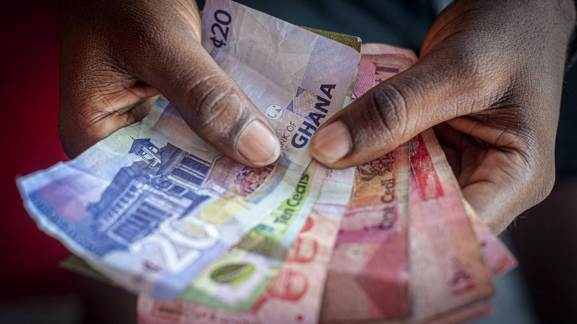A man holds a bundle of Ghanaian Cedi banknotes. - Sputnik Africa, 1920, 12.12.2024