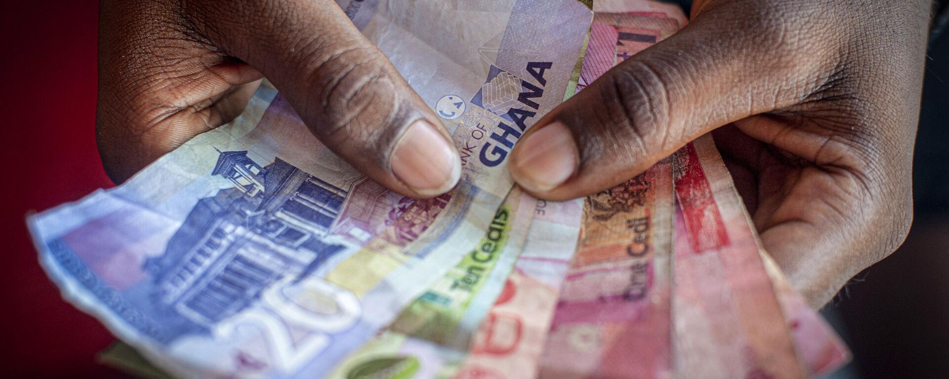 A man holds a bundle of Ghanaian Cedi banknotes. - Sputnik Africa, 1920, 12.12.2024