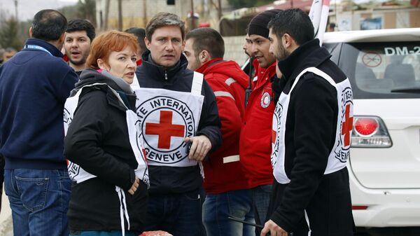 In this Jan. 11, 2016 photo, aid workers stand near a convoy of vehicles loaded with food and other supplies organized by the International Committee of the Red Cross, working alongside the Syrian Arab Red Crescent and the United Nations, makes it's way to the besieged town of Madaya, about 15 miles (24 kilometers) northwest of Damascus, Syria.  - Sputnik Africa