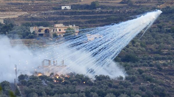 A shell that appears to be white phosphorus from Israeli artillery explodes over a house in al-Bustan, a Lebanese village along the border with Israel, on Oct. 15, 2023. - Sputnik Africa