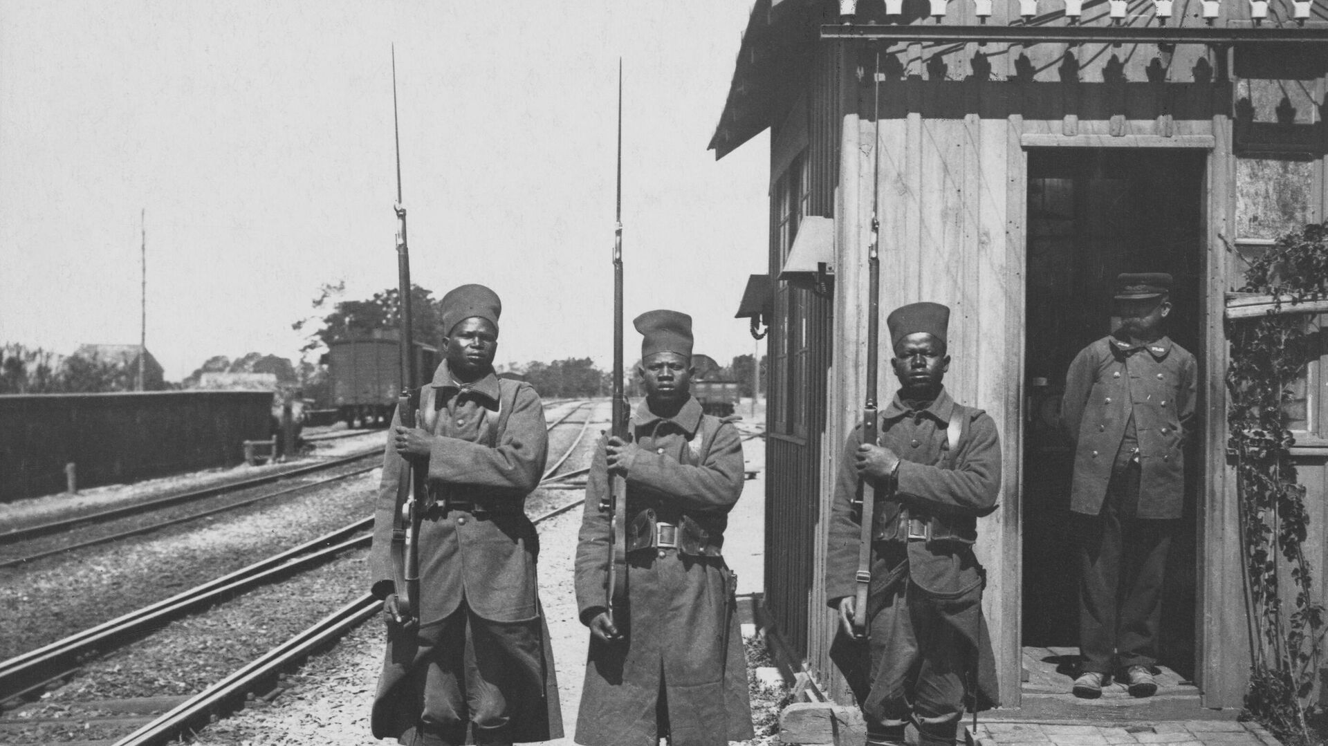 Three African soldiers from a unit of Bataillon Tirailleurs Sénégalais (Senegalese Riflemen) from the L'Infanterie Coloniale (Colonial Infantry) of the French Army present arms with their Lebel Model 1886/93 rifles and bayonets (the soldier in the center carries the Berthier Mle 1907/15 Rifle) whilst on guard duty at a railway station in France circa June 1915.  - Sputnik Africa, 1920, 01.01.2025