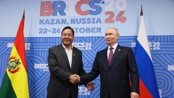 Bolivian President Luis Alberto Arce Catacora and Russian President Vladimir Putin shake hands as they pose for photos before a meeting on the sidelines of the 16th BRICS Summit in Kazan, Russia - Sputnik Africa