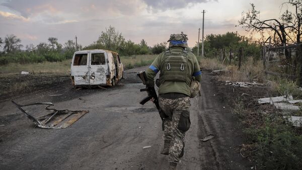 A serviceman of the 24th Mechanised Brigade runs past a damaged car at the frontline in Donetsk region.   - Sputnik Africa