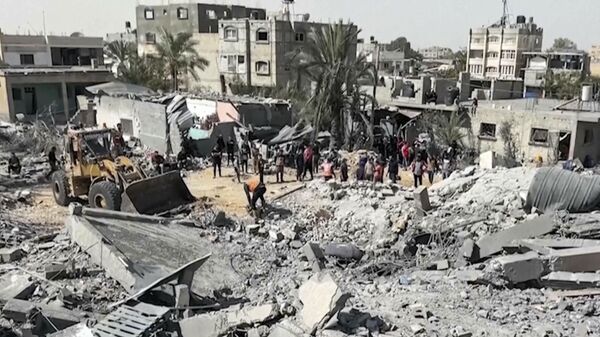 Palestinians gather near a building destroyed by Israeli airstrikes in the city of Khan Younis, southern Gaza Strip, Friday, Oct. 25, 2024.  - Sputnik Africa