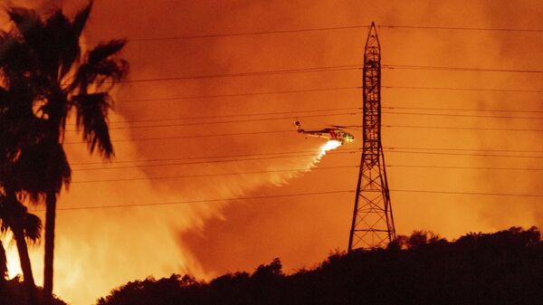 A helicopter drops water on the Palisades Fire in Mandeville Canyon, Friday, Jan. 10, 2025, in Los Angeles.  - Sputnik Africa