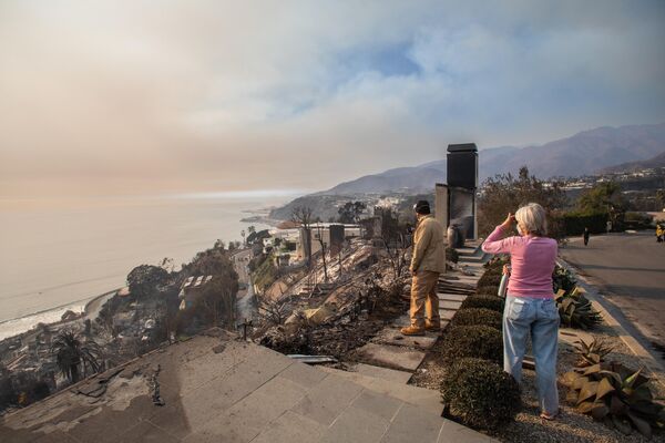 People look at houses burned by the Palisades Fire on January 9, 2025 in the Pacific Palisades neighborhood of Los Angeles, California. - Sputnik Africa