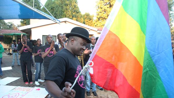 Samba Chesterfield, Director of Gays and Lesbians Association of Zimbabwe, prepares to hoist their official flag alongside the Zimbabwean flag during a belated commemoration of the May 17 International Day against Xenophobia and Transphobia in Harare, Zimbabwe, Saturday, May, 19, 2012.  - Sputnik Africa