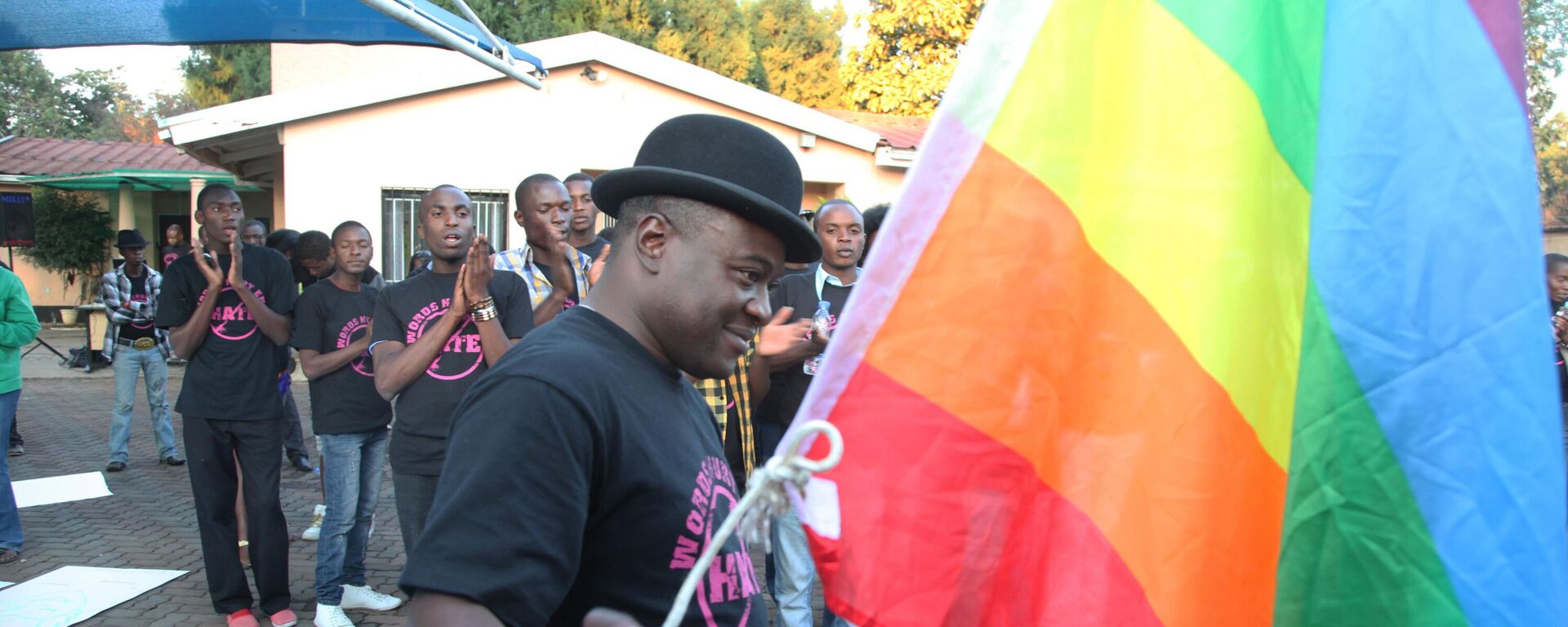 Samba Chesterfield, Director of Gays and Lesbians Association of Zimbabwe, prepares to hoist their official flag alongside the Zimbabwean flag during a belated commemoration of the May 17 International Day against Xenophobia and Transphobia in Harare, Zimbabwe, Saturday, May, 19, 2012.  - Sputnik Africa, 1920, 11.01.2025