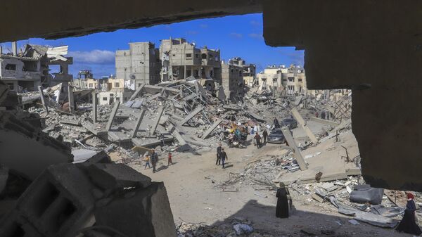 Palestinians walk through the rubble caused by the Israeli air and ground offensive in Rafah, southern Gaza Strip, Monday, Jan. 20, 2025. - Sputnik Africa