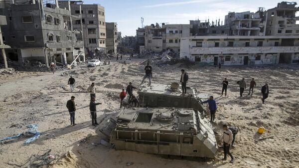 Palestinian youth walk atop the remains of military armored vehicles left behind after the Israeli air and ground offensive against Hamas, in Rafah, southern Gaza Strip, Monday, Jan. 20, 2025. - Sputnik Africa