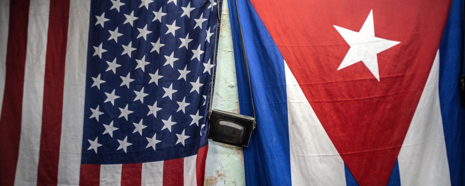 A US and Cuban flags hang from a wall with an old photo camera hung in between in Havana, Cuba, Monday, Jan 11, 2021.  - Sputnik Africa, 1920, 22.01.2025