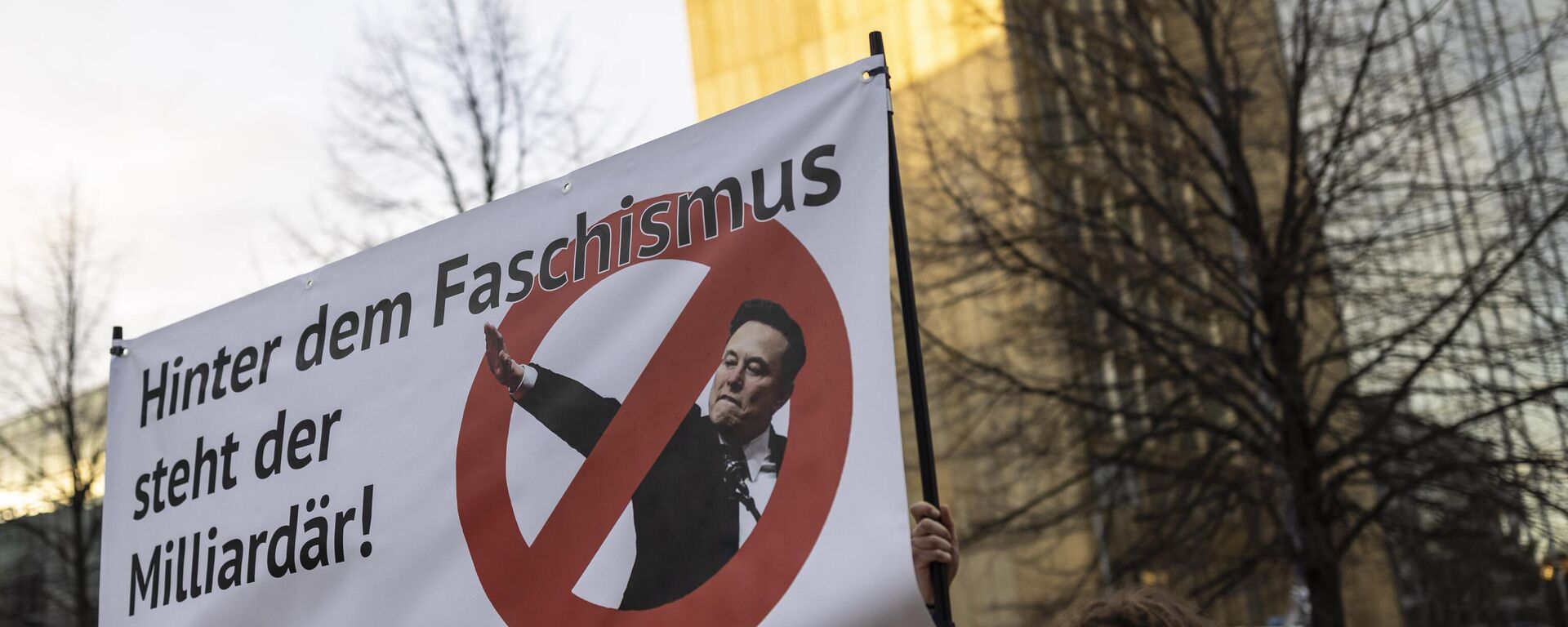 Protesters outside the WELT Economy Summit hold up a placard that reads Behind fascism is a billionaire, criticizing tech billionaire Elon Musk on January 27, 2025 in Berlin, Germany.  - Sputnik Africa, 1920, 28.01.2025