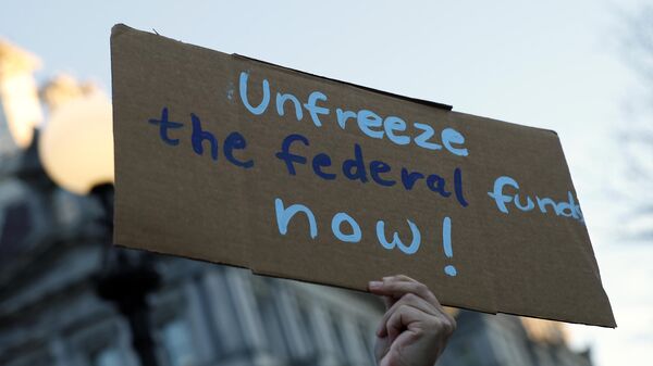 An activist protests against President Donald Trump's plan to stop most federal grants and loans during a rally near the White House on January 28, 2025 in Washington, DC. - Sputnik Africa