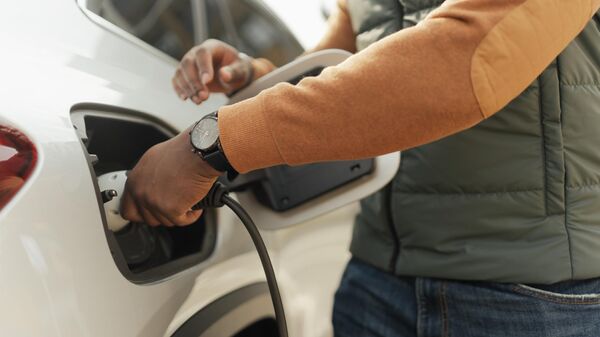 Young multiracial man charging his electric car, close-up. - Sputnik Africa