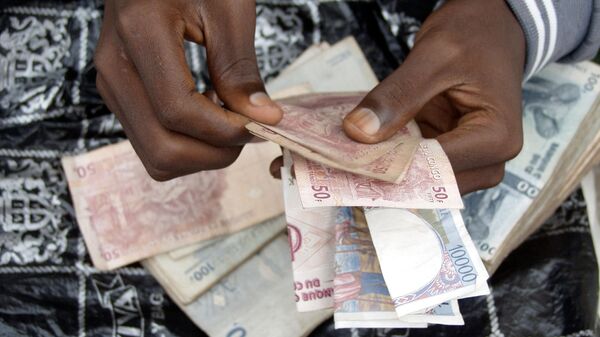 A man counts Congolese Francs on the street on February 28, 2002 in central Kinshasa, Congo. - Sputnik Africa