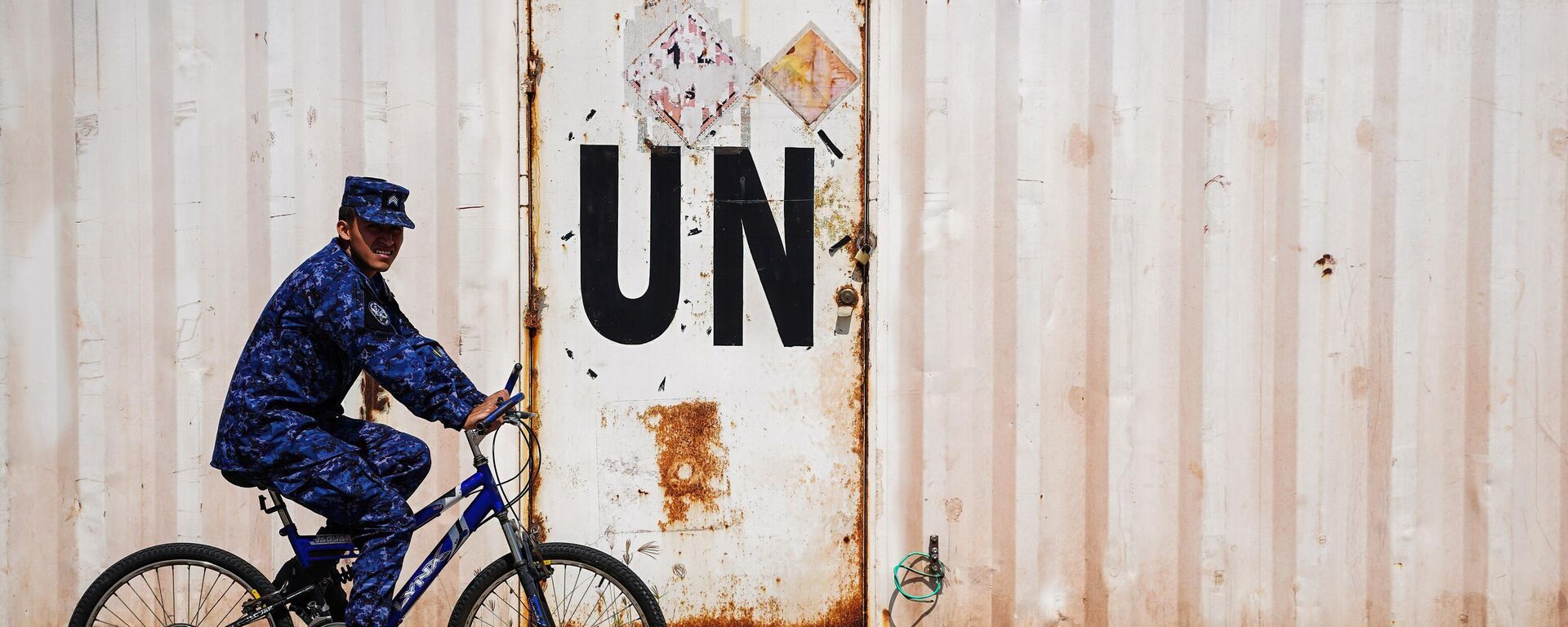 A soldier rides a bicycle next to a container with a UN label before deployment to Haiti as part of a UN Multinational Security Support Mission, in Ilopango. - Sputnik Africa, 1920, 06.02.2025