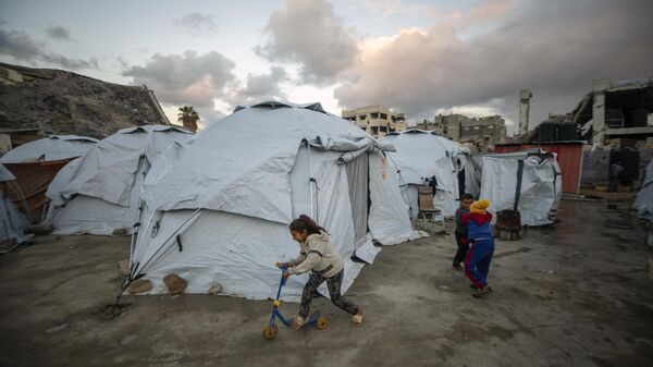 Children play at a tent camp for displaced Palestinians in Gaza City's Jabalya refugee camp, Thursday, Feb. 6, 2025, after collecting donated food.  - Sputnik Africa