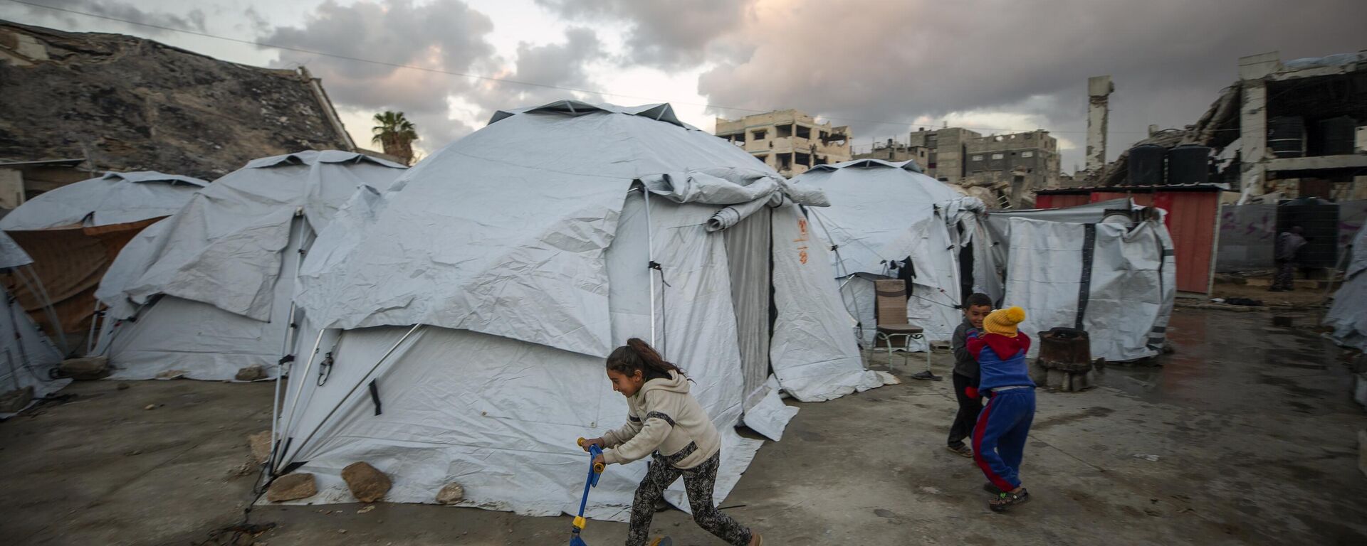 Children play at a tent camp for displaced Palestinians in Gaza City's Jabalya refugee camp, Thursday, Feb. 6, 2025, after collecting donated food.  - Sputnik Africa, 1920, 07.02.2025