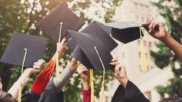 A group of multietnic students celebrating their graduation by throwing caps in the air closeup. Education, qualification and gown concept. - Sputnik Africa