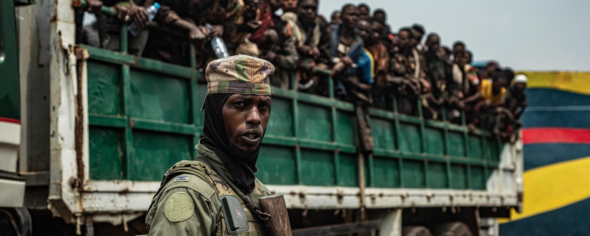 An M23 fighter stands in the foreground as detained FARDC soldiers are loaded onto trucks, to be taken to an unknown location, as an estimated 2400 Congolese (FARDC) soldiers surrendered en masse to M23 forces at the Stade de l'Unite on January 30, 2025 in Goma, Democratic Republic of Congo.  - Sputnik Africa, 1920, 21.02.2025