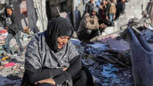 A woman sits amongst damaged homes caused by Israeli air strikes, on January 18, 2024 in Rafah, Gaza. - Sputnik Africa